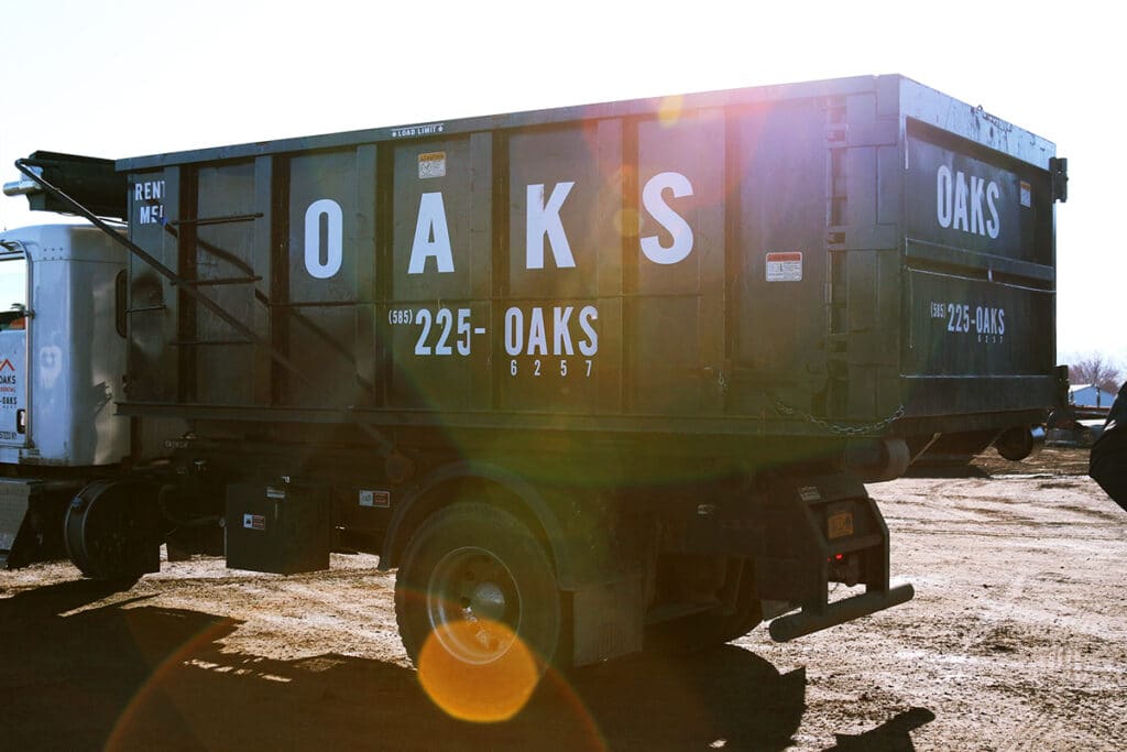 A black Oaks dump truck parked on a dirt lot. Oaks truck for rent.