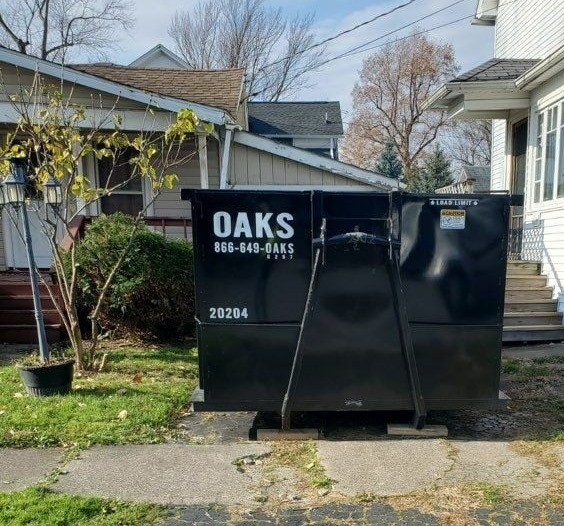 A large black dumpster with the word OAKS on it.