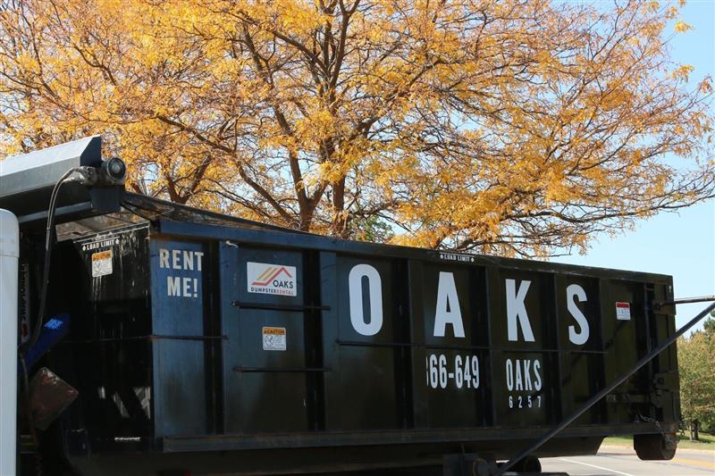 A black dumpster with 'Oaks' and phone number '330-349-3493'.