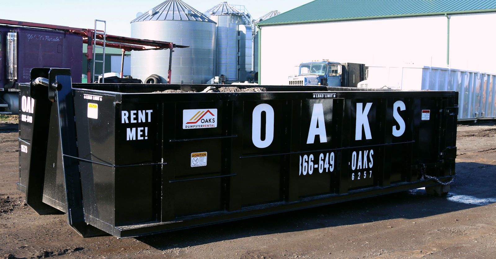 A black dumpster with 'Oaks' and 'Rent Me' text on it.