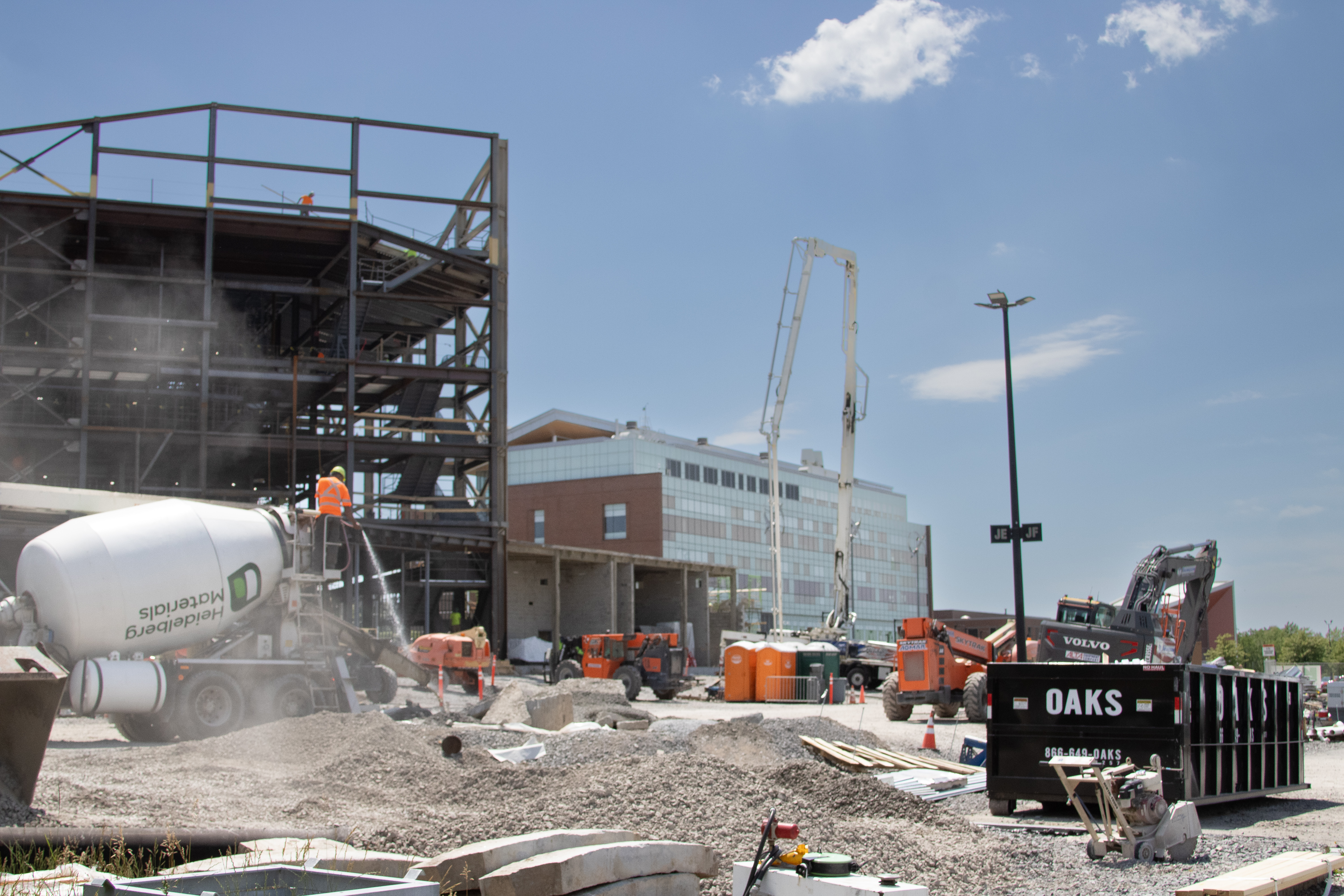 Construction site with workers and heavy machinery. A cement mixer is in the foreground.