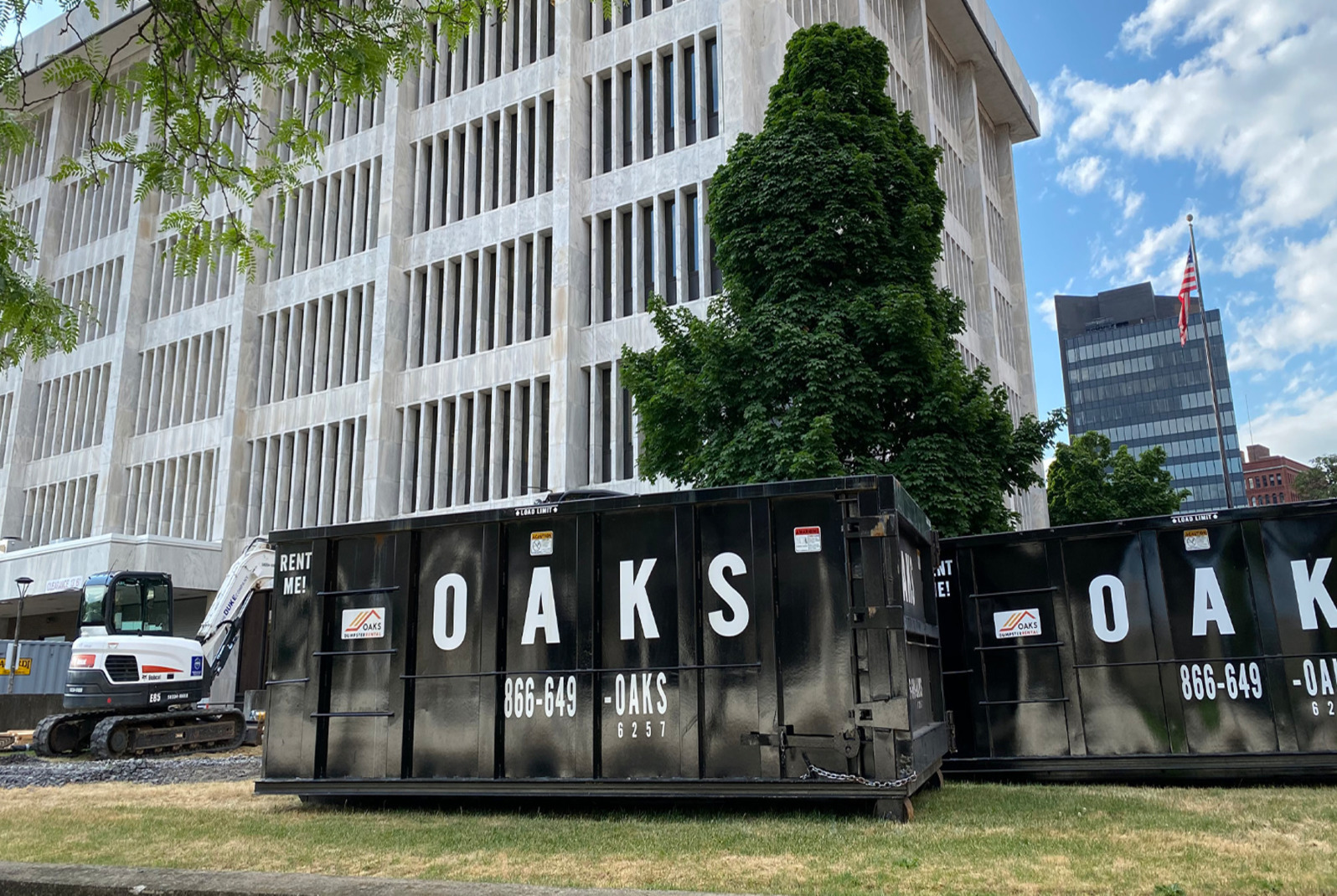 black dumpster on a grassy area. It has white lettering.