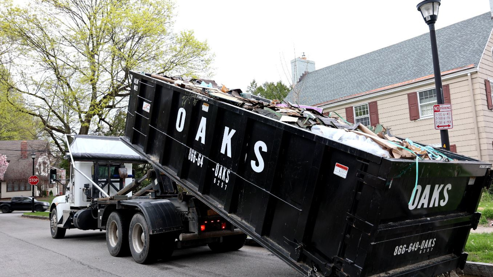 A large black dumpster on a truck on the street