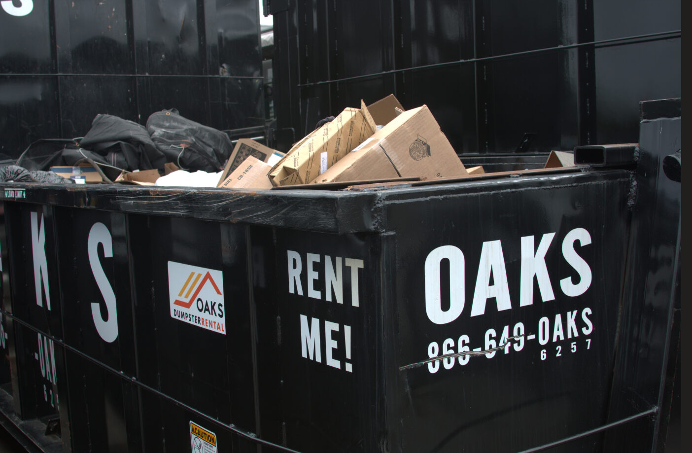 A dumpster filled with cardboard boxes and trash. Rent me!