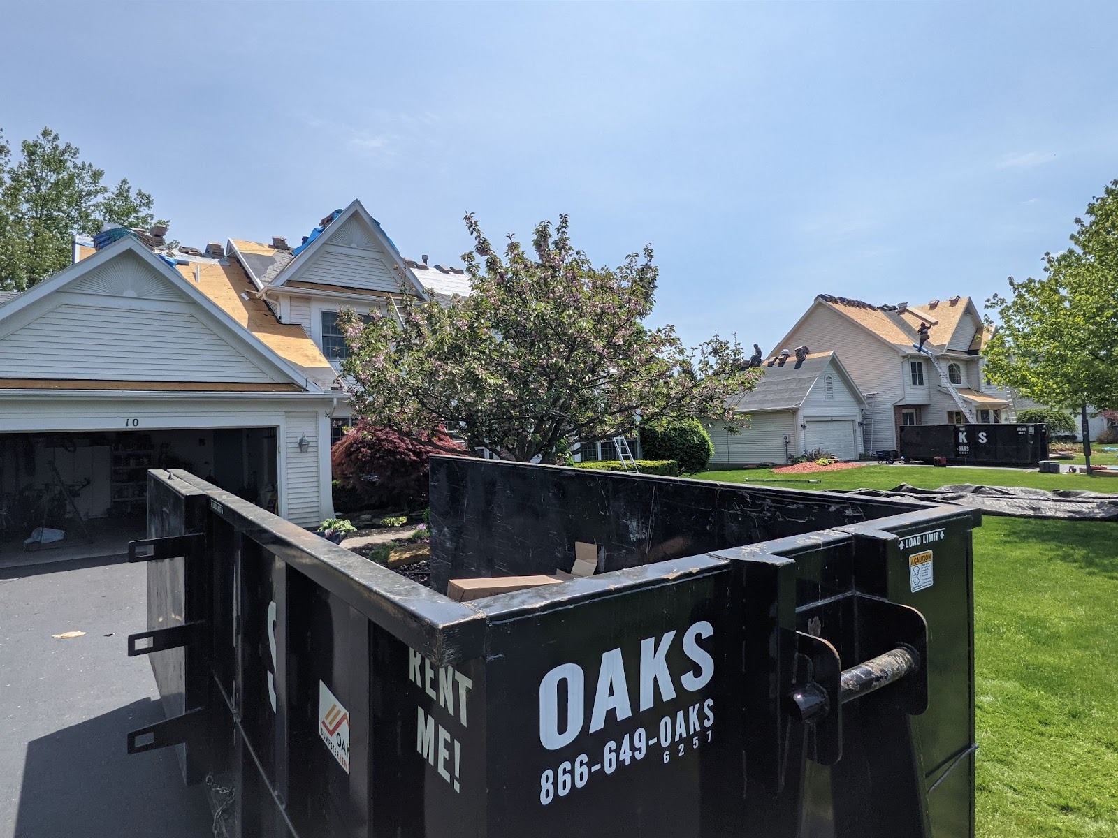 A black dumpster with Oaks logo and phone number