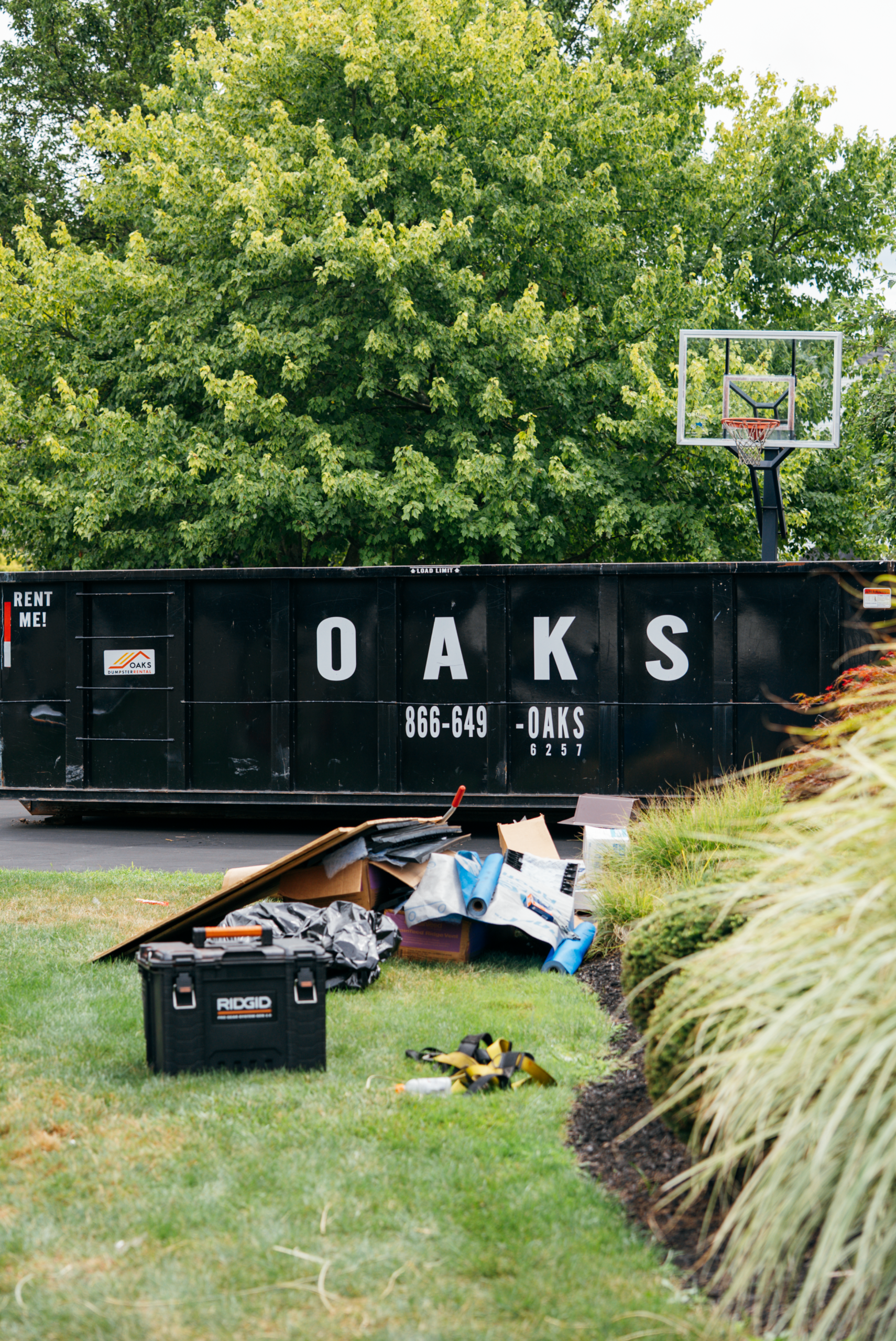 A black dumpster with Oaks logo and a pile of debris