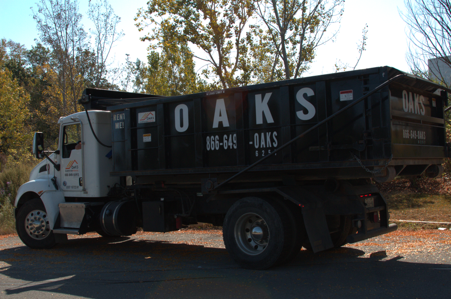 A large black dump truck with Oaks written on the side. The truck has a white cab.