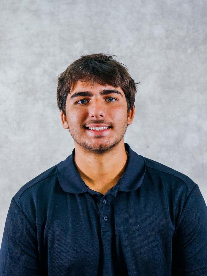 Smiling man in a dark navy polo shirt against a neutral backdrop