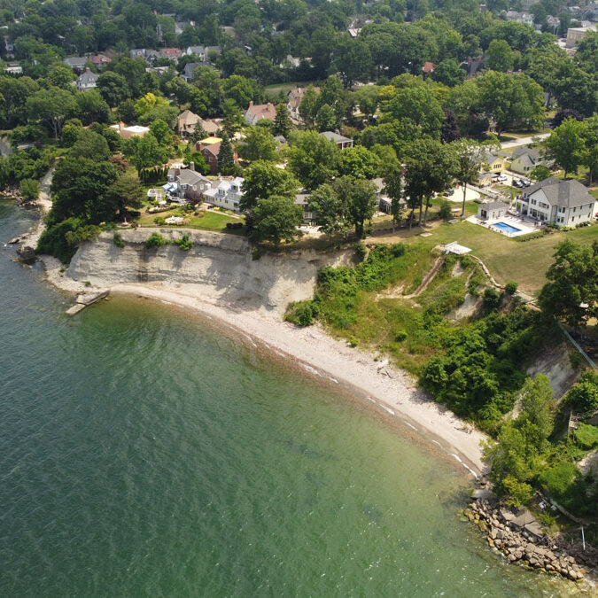 A beach with clear water and a cliffside neighborhood