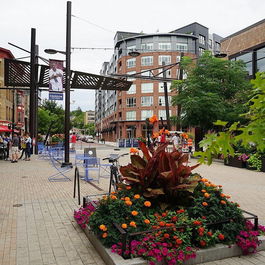 a city street with a flower planter and people walking