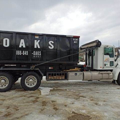 a large truck with a black dumpster on the back