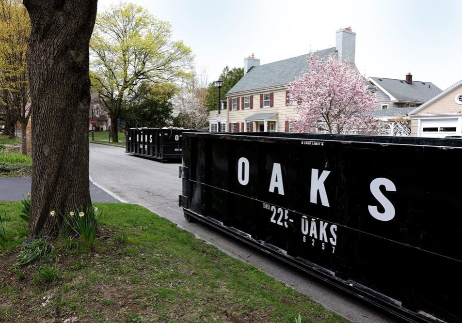 row of black dumpsters on a suburban street