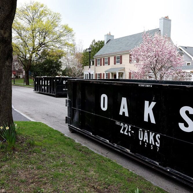 row of black dumpsters on a suburban street